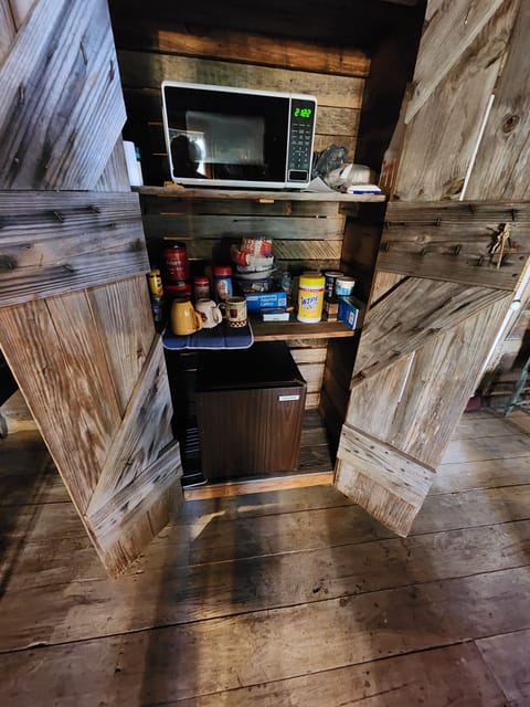 Wooden cabinet holds microwave & Frigerator, coffee, cutlery, plates,& cups