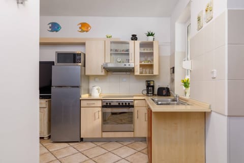 A fully equipped kitchen featuring wooden cabinetry, a refrigerator, and essential appliances.
