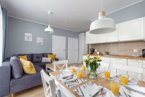 Another angle of the living room, emphasizing the comfortable gray sofa and dining area. The space is well-lit by natural light from large windows.