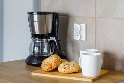 A close-up of a coffee maker, white cup, and other essentials on the kitchen counter. The arrangement is both functional and inviting.