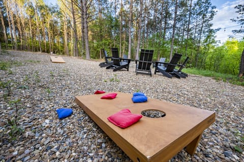 Cornhole & chill—outdoor setup with Adirondack chairs in the forest!
