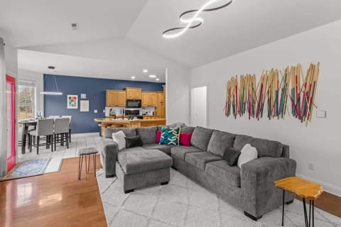 Unwind in the open-concept living area with a plush sectional, 65″ smart TV & cozy fireplace—the perfect spot to relax after a day on the trails.