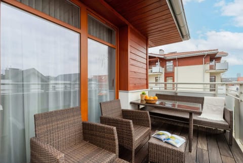 A spacious balcony with wicker furniture, offering a relaxing spot to enjoy outdoor views.