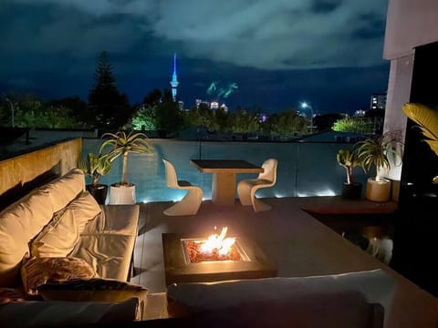 City lights beyond the Western Park foliage provide a backdrop to the gas fire pit