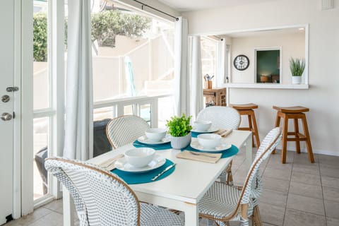 Bright dining area with white wicker chairs and large windows ov