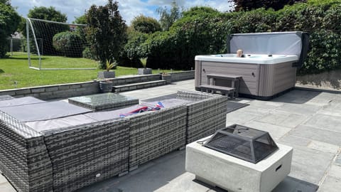 Patio features rattan furniture, fire pit and hot tub.