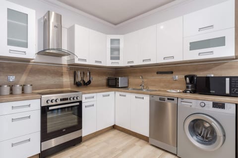 A modern kitchen with white cabinets, built-in appliances.