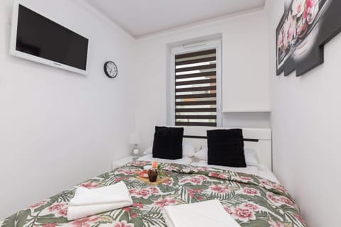 A bedroom with a comfortable double bed, floral bedding, bedside lamps, and stylish decor elements such as floral artwork on the wall.