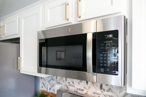Stainless steel microwave above gas range for easy cooking   - Sleek design with modern backsplash and white cabinetry   - Convenient appliance setup for quick meals and snacks