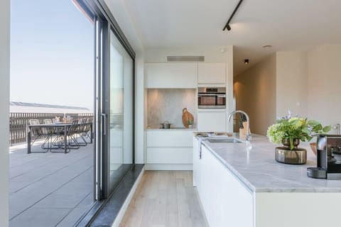 Sleek kitchen opening onto a sunny terrace.