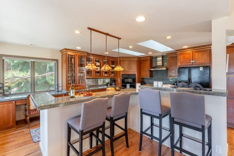 Fully-equipped kitchen with modern appliances, a workspace, and barstool seating at the counter.