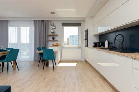 A fully equipped kitchen with sleek white cabinets and a contrasting black backsplash.