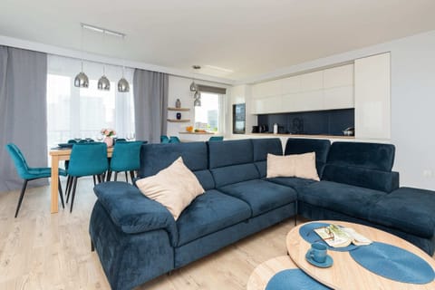 A bright and open living area featuring a large blue sectional sofa, a coffee table, and modern decor.