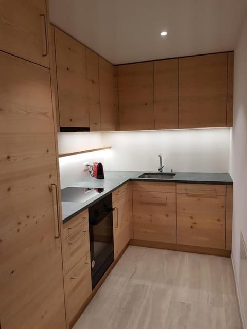 Kitchen (2020) by the Engadiner Lehrwerkstatt Samedan using Engadine larch wood and serpentine stone from Puschlav