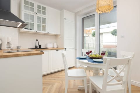A modern kitchen with white cabinets, wooden countertops, and a dining area by the window.

