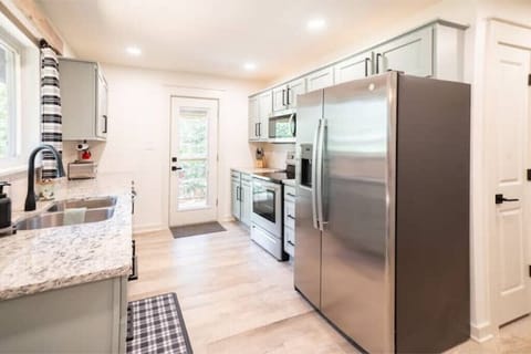 Kitchen leads to covered deck with gas grill