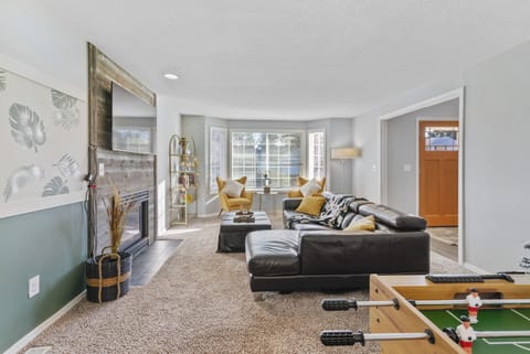 comfortable leather couch, accent chairs, decorative fireplace and 65" smart TV