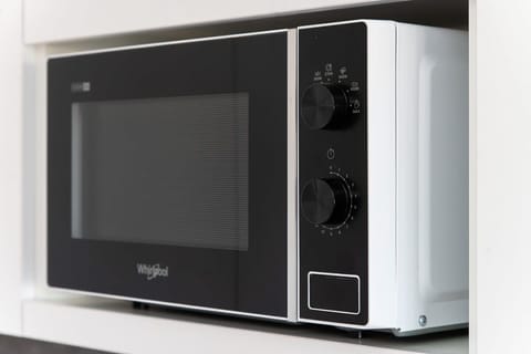 A microwave neatly placed on a white countertop, showcasing a modern and functional appliance setup.
