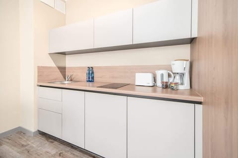 A modern kitchen with white cabinets and wooden accents, equipped with appliances for convenience and style.