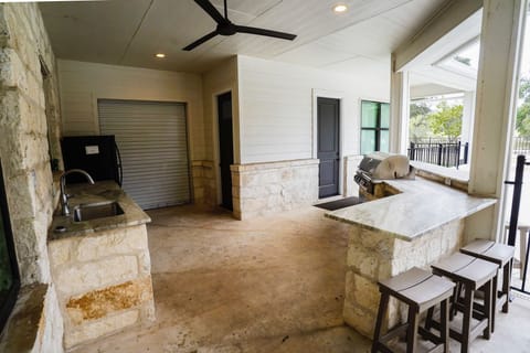 Outdoor kitchen has plenty to offer with sink, fridge, and built in grill.