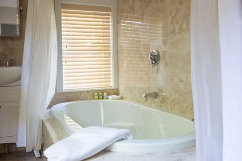 Deluxe Suite, 1 Bedroom, Jetted Tub | Bathroom | Combined shower/tub, rainfall showerhead, designer toiletries