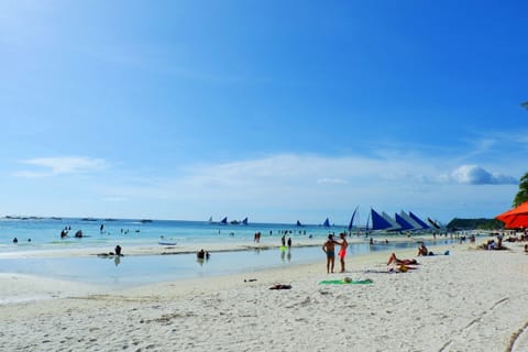 Beach nearby, white sand, beach towels, motor boating