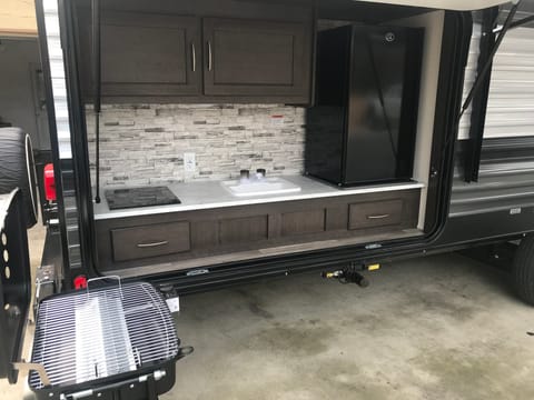 Full outdoor kitchen with propane bbq, electric cook top, sink and out door fridge 