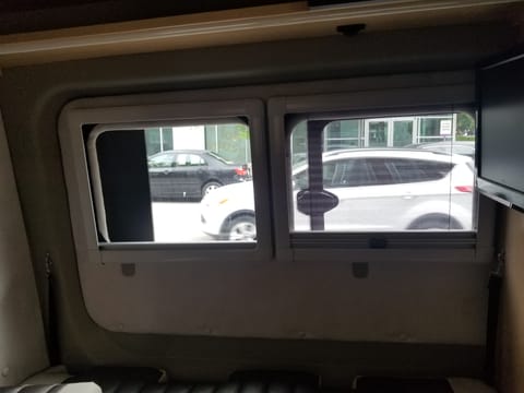 This is the rear of the van looking the windows on the driver's side.  The window to the right can be opened and has a bug screen.  There's a TV on the wall to the right of the windows..