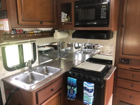 spacious cabinet over sink...microwave over full stove another cabinet to the left with drawers below.