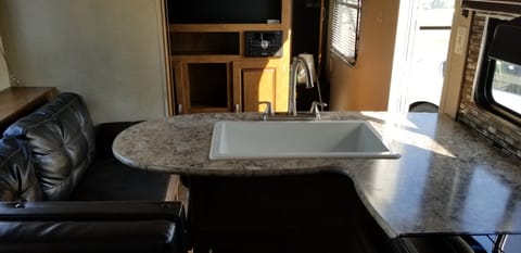 Large kitchen sink, entertainment centre. Slide-out is pulled in, in this photo. Large counter space as compared to most rv's. Room for a dish drainer, meal prep, and even a bouquet of flowers! Master bedroom is behind the entertainment centre which has a built-in radio, tv hookups and DVD player. Also hooked up to exterior speakers so you can enjoy your music or sports program while enjoying the outdoors.