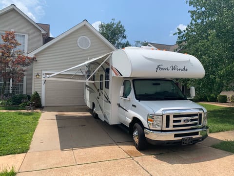 Front and side of RV with awning out.