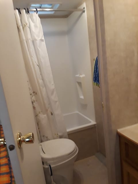 Bathroom with bathtub, toilet, and towel bar and hooks. 