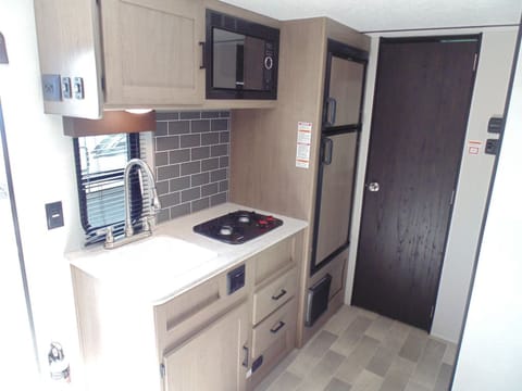 Kitchen with sink, microwave, stovetop and storage (door is to bathroom)