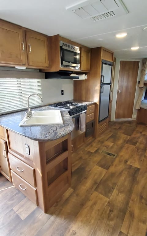 Kitchen with double sinks, oven, 3 burner stove, and microwave.