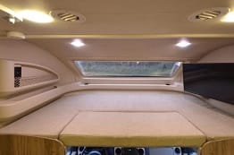 Top cab sleeping area with tv and panoramic window with power shades.