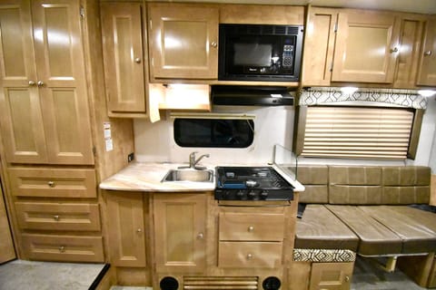 Kitchen area with a nice countertop, 3-burner stove, microwave, range hood, etc.