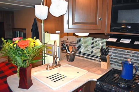Full kitchen with large sink, 3 burner stove, microwave, small oven, mid-size fridge an freezer