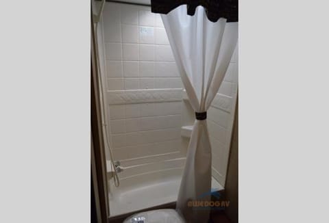 Shower and bathtub in bathroom with fan and exhaust at the top.