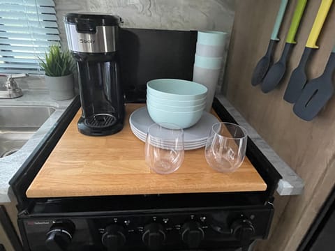 Eleanor comes with 4 plastic tumblers, 4 bowls, 4 plates, 2 plastic stemless wine glasses, and a coffee maker that uses k-cups.