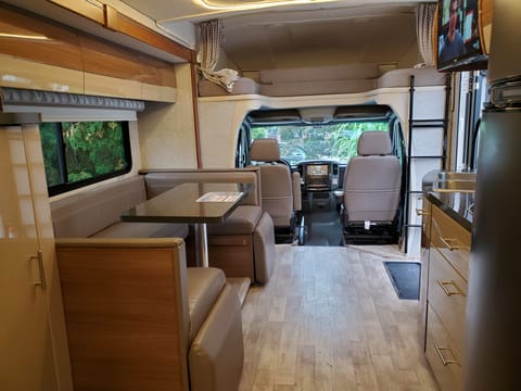 1st TV above the kitchen area with flip up foot rests to turn area into a lounge for comfort. 
4 seat belts in dining area. Sleeping area above cab