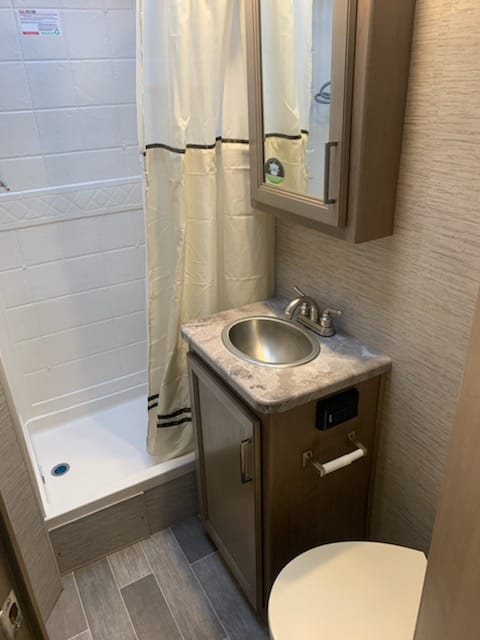 Private bathroom with shower, sink, and toilet, medicine cabinet, locked door