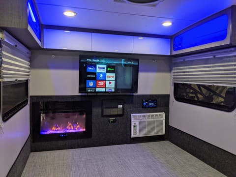 A roomy space featuring a fireplace, AC, Stereo, and smart TV. 