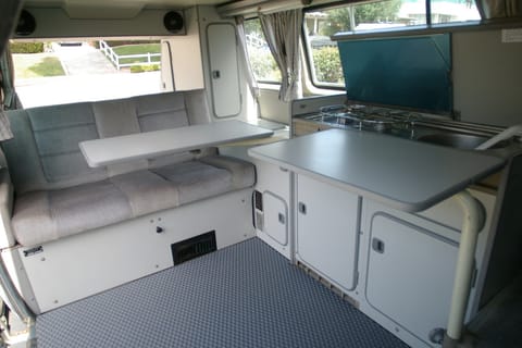 The classic westfalia interior has two fold out tables, a two burner propane stove, a small fridge, and plenty of storage. 