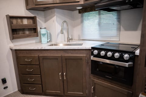 The Keystone Passport Kitchen features a 3-burner stove with oven, microwave, refrigerator and Keurig!