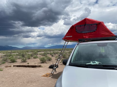Exterior view of the tent and ladder, with the stormy Sangre de Cristo range in the background. 