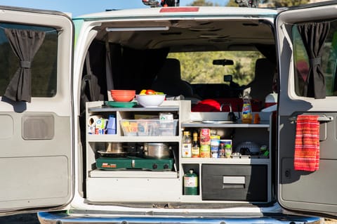 The built-in kitchen in Escape Campervans comes with a two-burner propane stove, a sink, a solar-powered fridge, overhead lighting, and enough storage for all your food. 