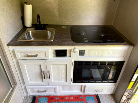 The kitchen boasts a sink, 3 burner propane stove, and microwave (microwave operable on shore power). We include dishes, pots, pans, and spices!