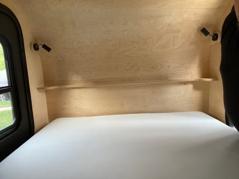 Interior photo showing full size bed facing the front of the trailer. All lights run on either Lithium battery or electric hook-up. 