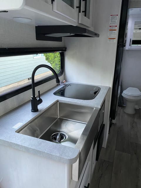 Features a large sink, propane powered stovetop, and microwave. 