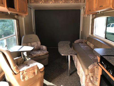 Inside view of the pull-out sofa sleeper with the bunk-beds stowed away. You'll see the two captains chairs and tables for eating. 